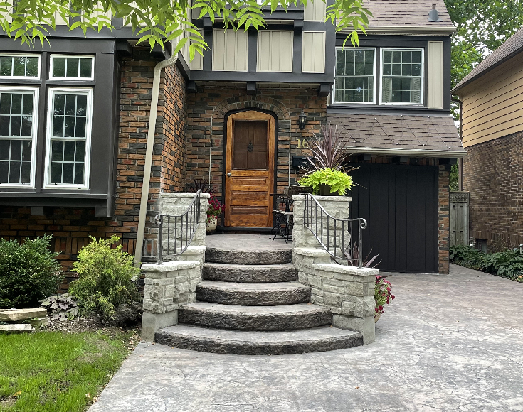 Modernized front entryway after renovation featuring new stone-faced stairs and decorative stamped concrete walkway in London Ontario