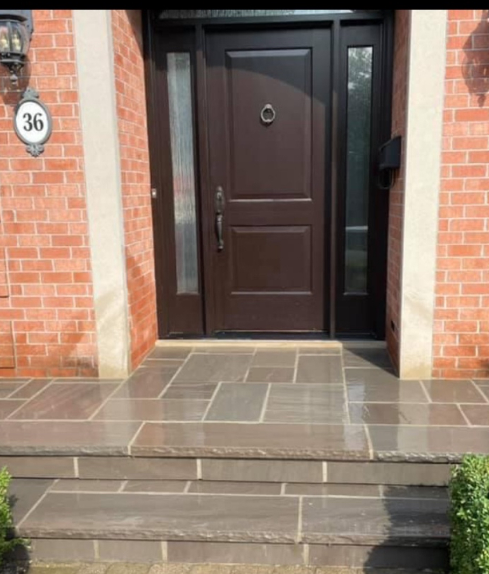 Refinished front steps and porch after restoration with modern large-format natural stone and clean grout lines in London Ontario